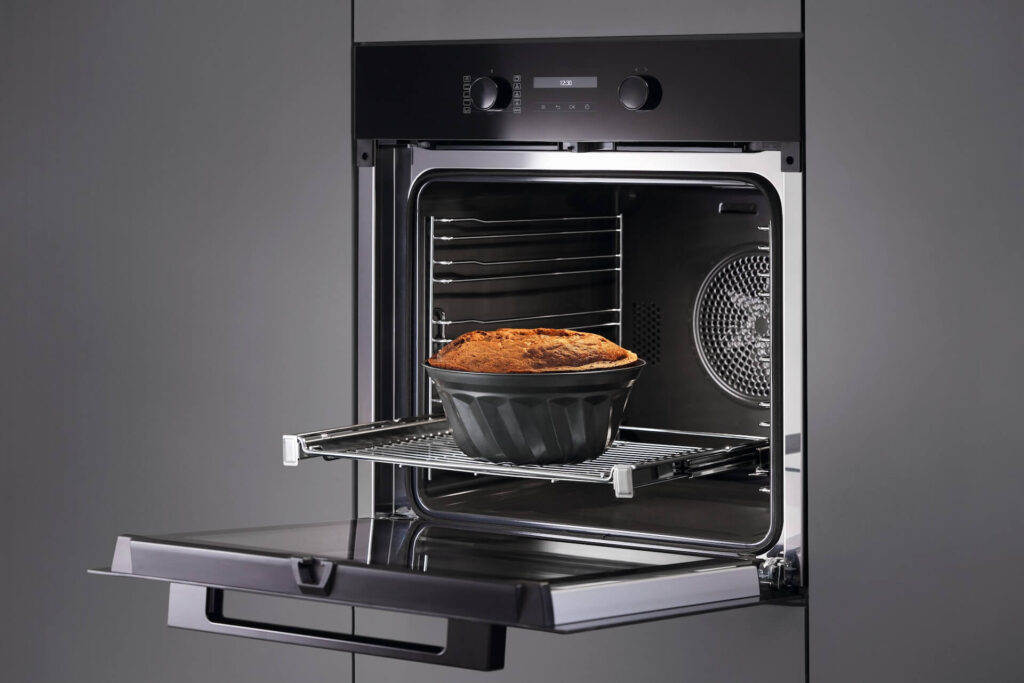 Miele Backofen Obsidianschwarz mit geöffneter Klapptür und ausgezogenem Rost